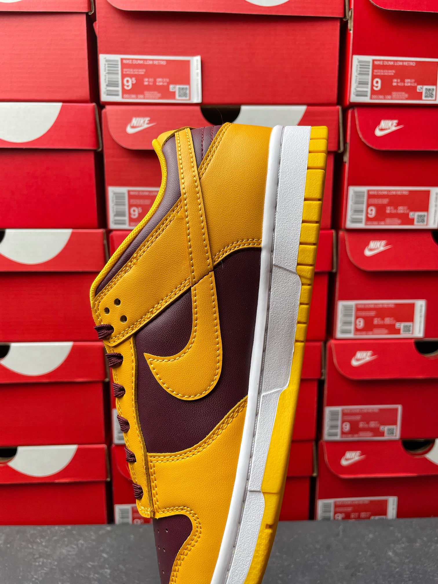 Nike Dunk Low side view showing yellow toe and dark purple swoosh on white sole