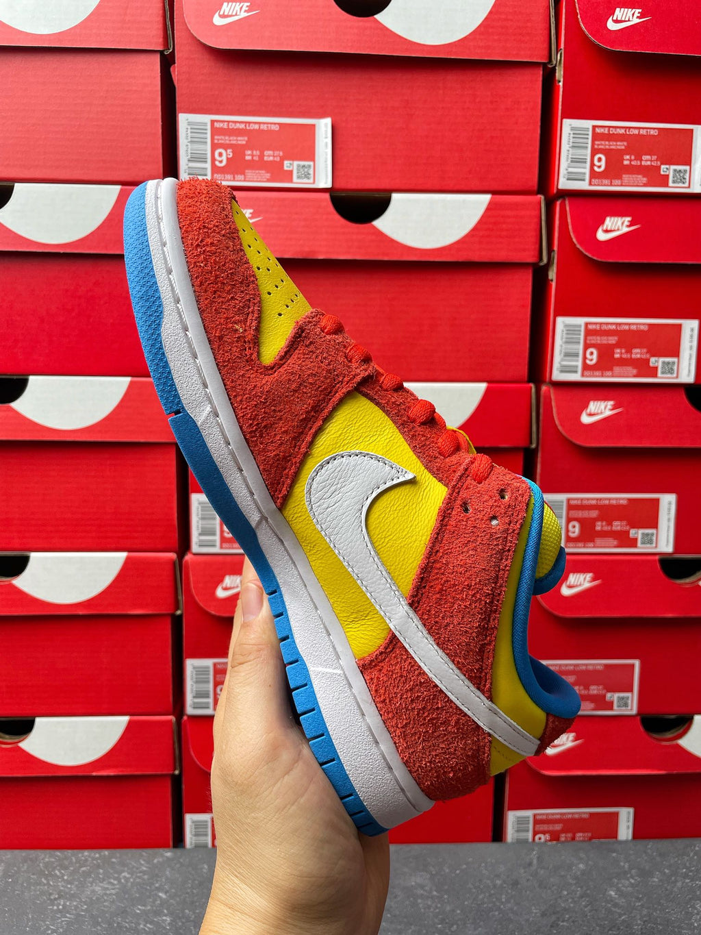 Nike Dunk Low sneaker, toe and side view with red suede, yellow swoosh, blue outsole