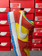 Nike Dunk Low sneaker, close-up side profile with yellow swoosh and blue outsole