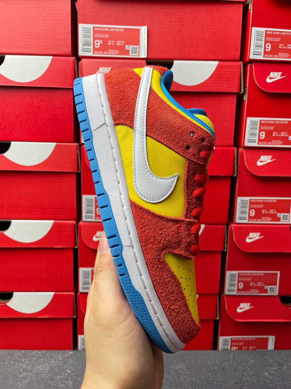 Nike Dunk Low sneaker, red suede with yellow panels, white swoosh, blue outsole view