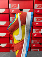 Nike Dunk Low sneaker, angled side view with red suede, yellow swoosh, blue outsole