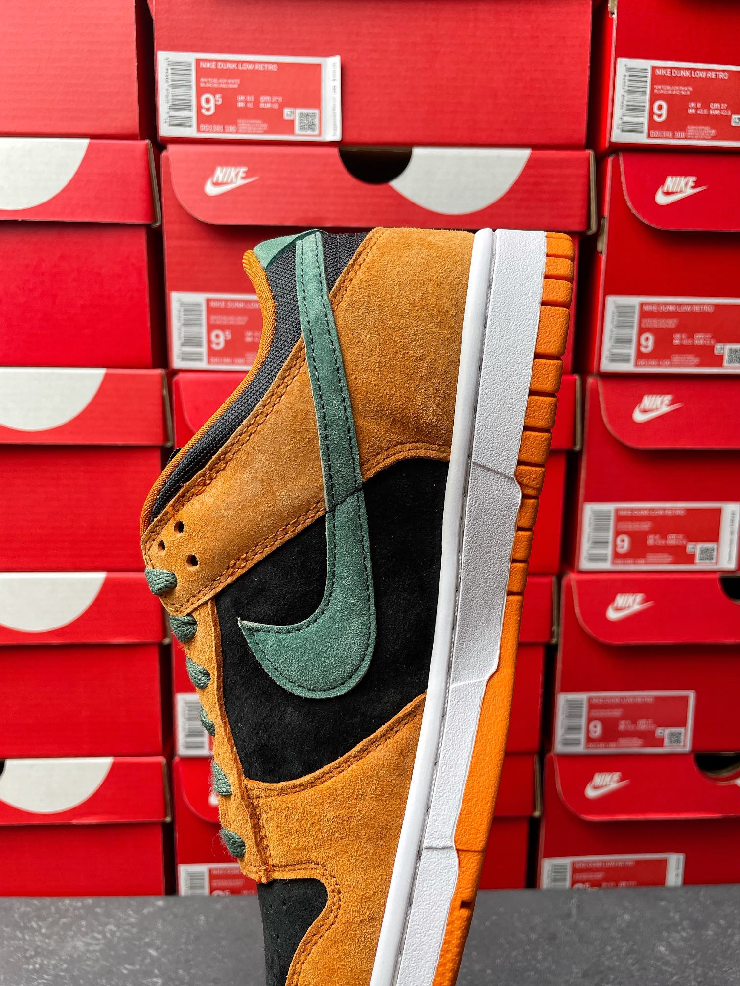 Nike Dunk Low sneaker angled view with orange suede, teal swoosh, black panels, white midsole