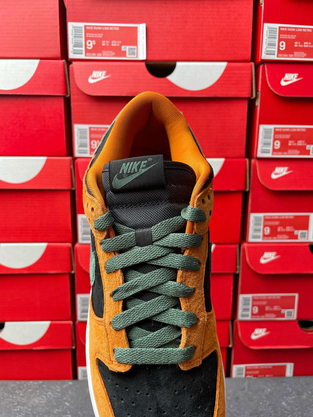 Nike Dunk Low shoe with orange suede upper, green laces, and black tongue with white sole