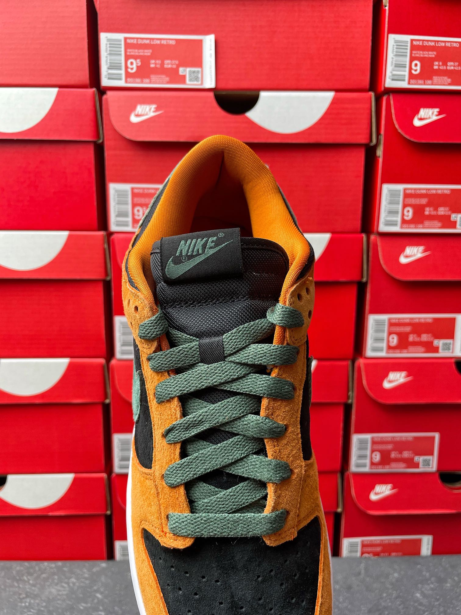 Nike Dunk Low shoe with orange suede upper, green laces, and black tongue with white sole