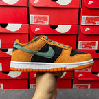Nike Dunk Low sneakers with orange suede, green swoosh, black panels, and white sole