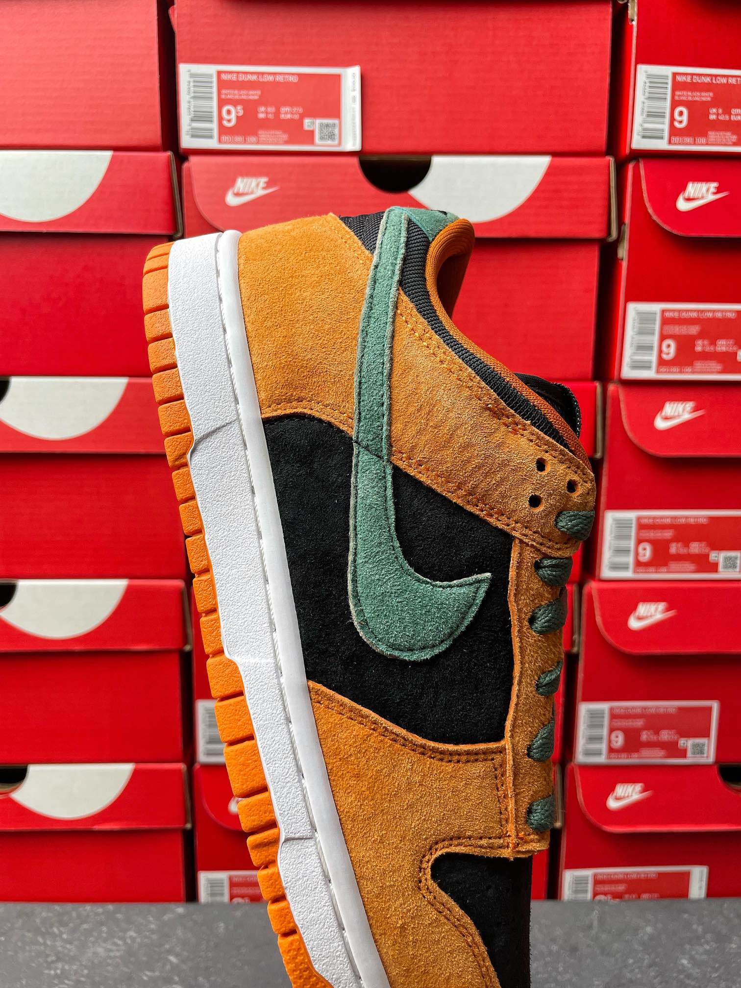 Nike Dunk Low sneaker side view with orange suede, green swoosh, black overlays, white sole