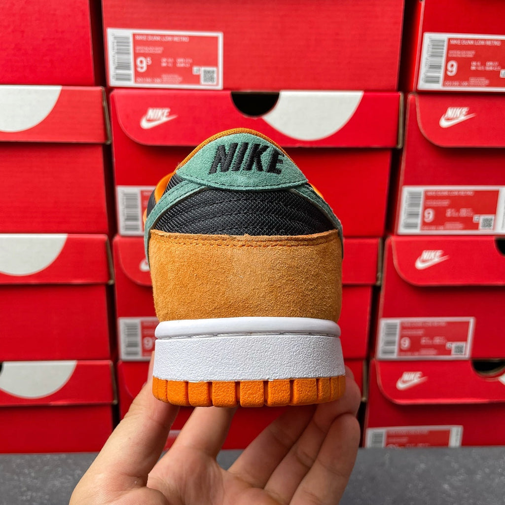 Nike Dunk Low sneaker heel view with orange suede back, white midsole, and black Nike logo