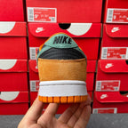 Nike Dunk Low sneaker heel view with orange suede back, white midsole, and black Nike logo