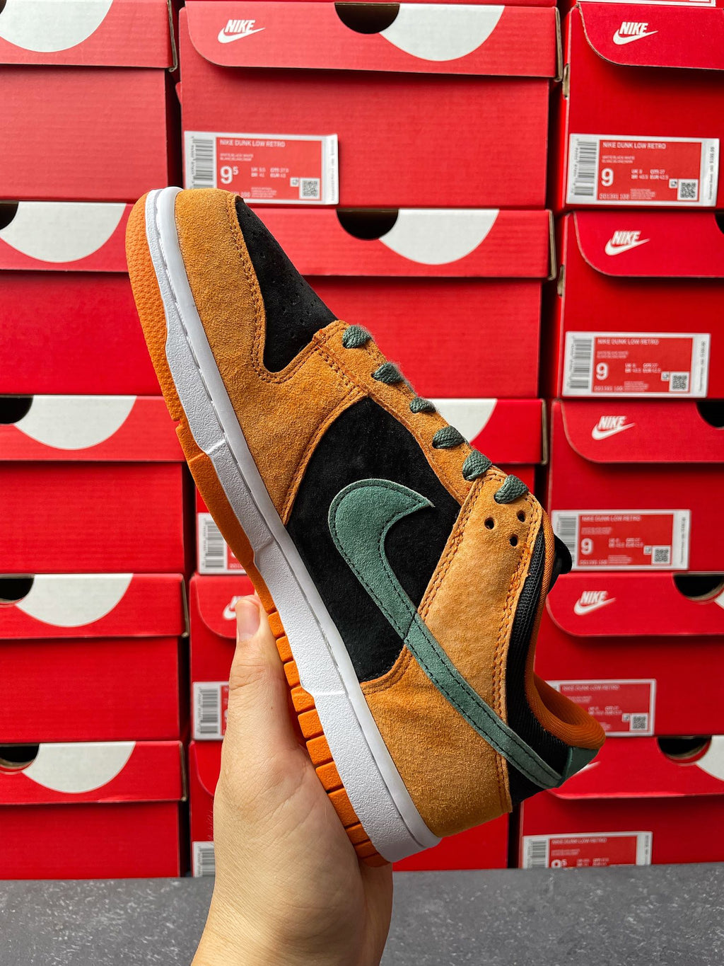 Nike Dunk Low sneaker back-quarter view with orange suede, green swoosh, and black side panel
