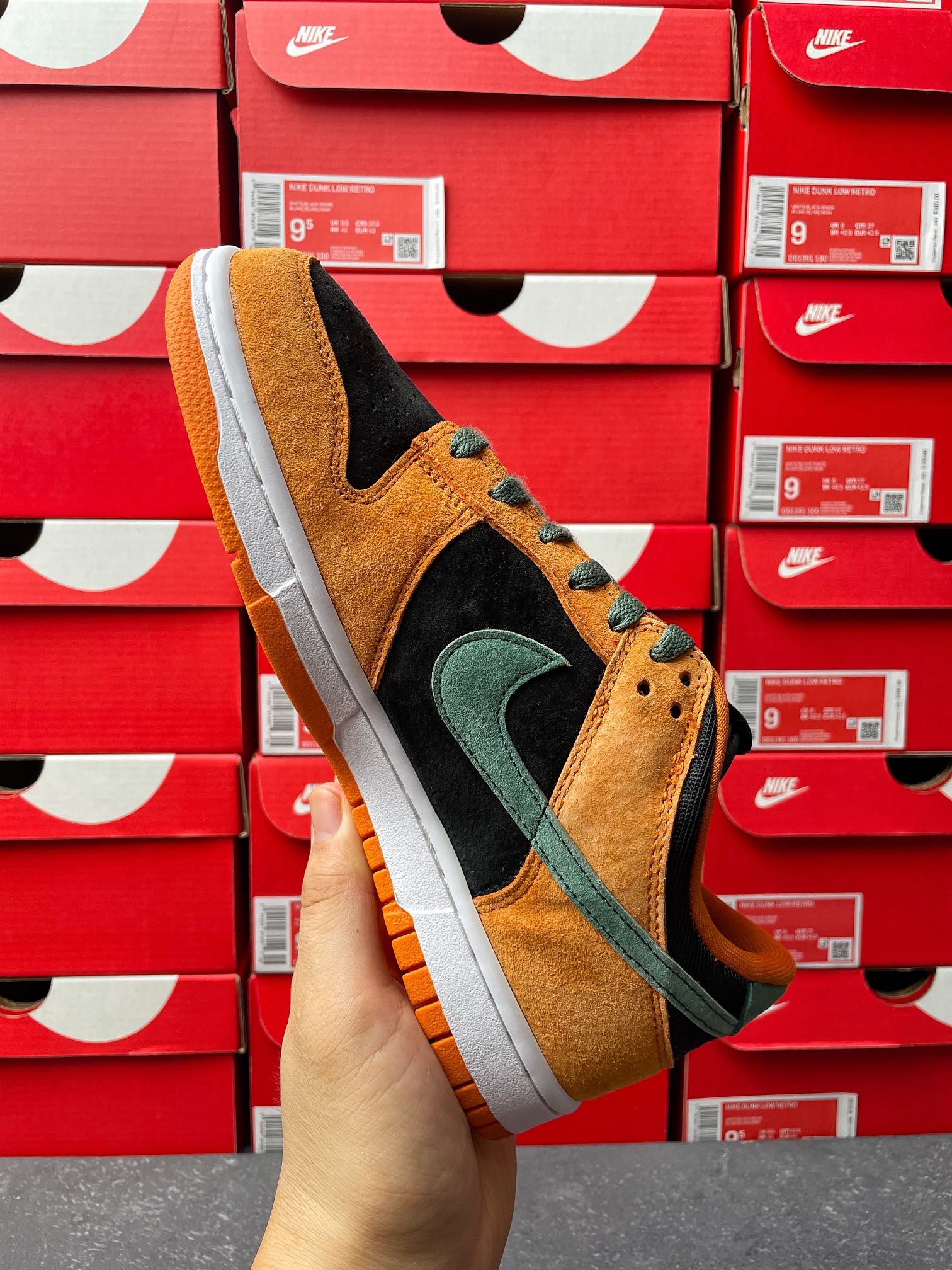 Nike Dunk Low sneaker back-quarter view with orange suede, green swoosh, and black side panel