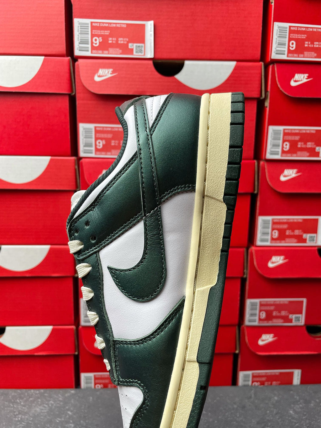 Nike Dunk Low sneaker quarter view in dark green, white panels, and cream sole