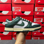 Nike Dunk Low sneaker with dark green leather, white Swoosh, and cream sole