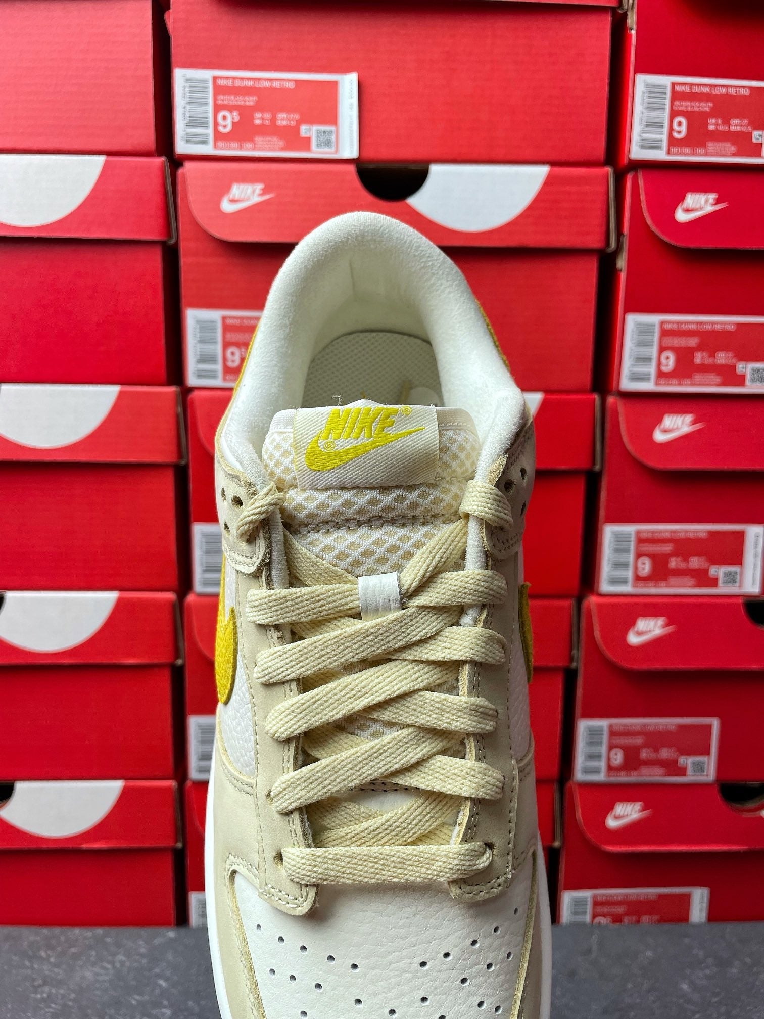 Nike Dunk Low sneaker, top view; cream woven laces with lemon accent at tongue