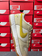 Nike Dunk Low sneaker, angled side view; cream panels and lemon-yellow swoosh