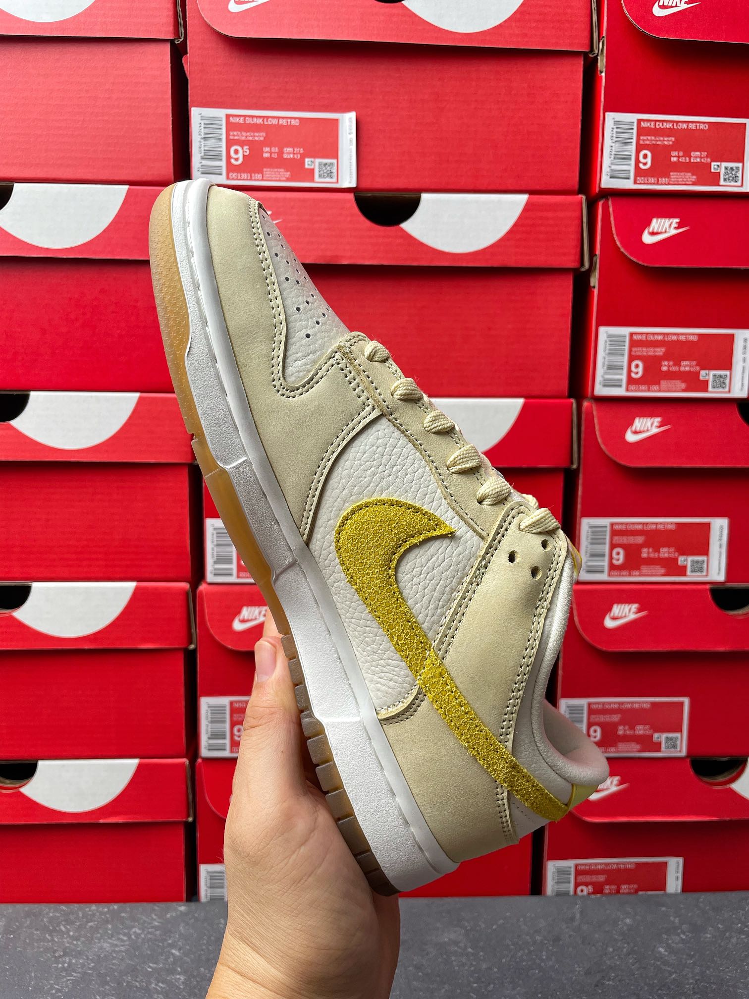 Nike Dunk Low sneaker, front side view; cream upper with lemon-yellow swoosh