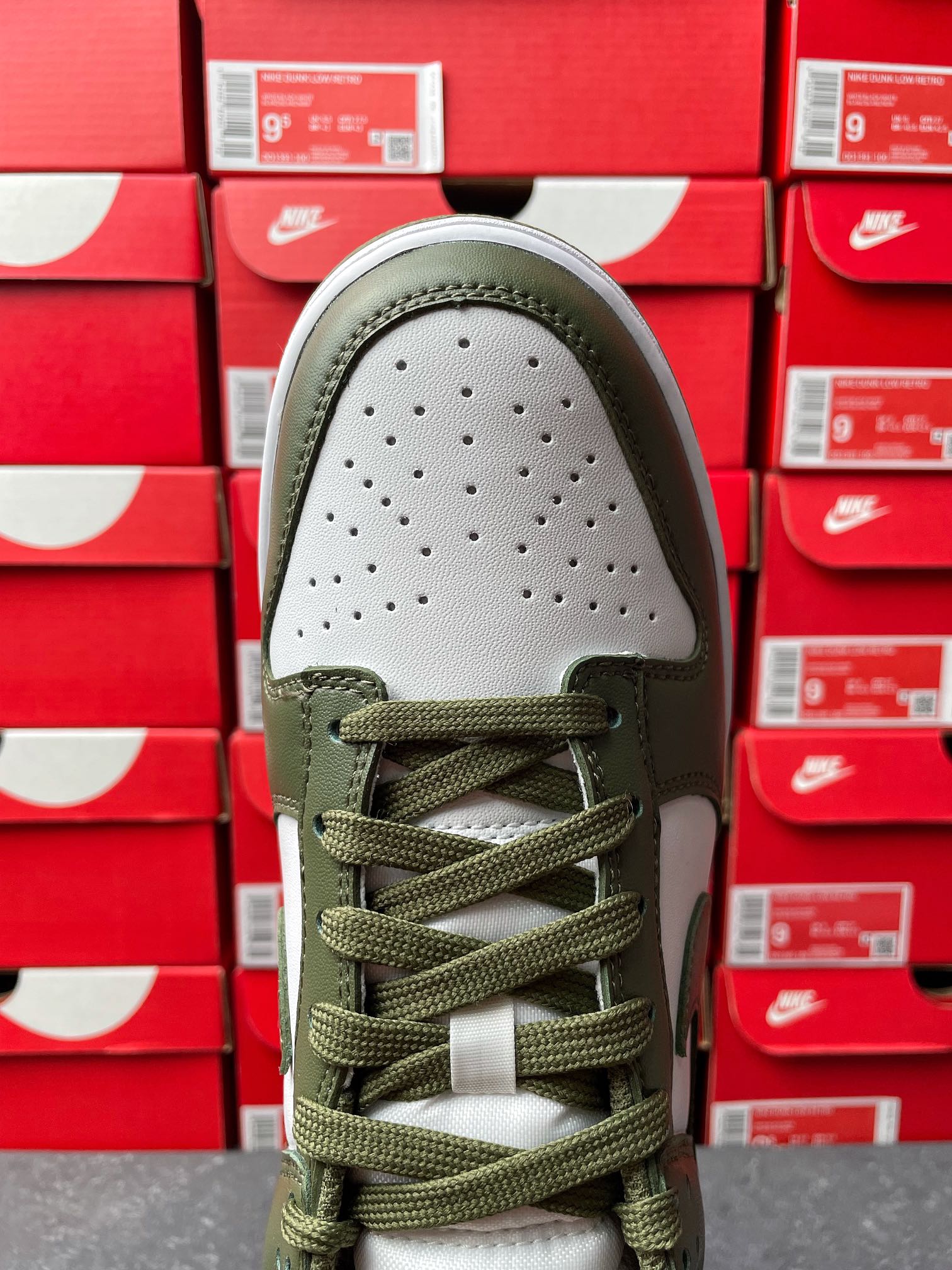 Low-top sneaker toe box in white with perforations, olive laces and olive collar.