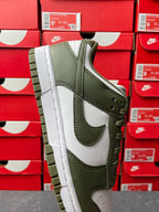 Low-top sneaker in olive green and white with stitched overlays and lace-up front.
