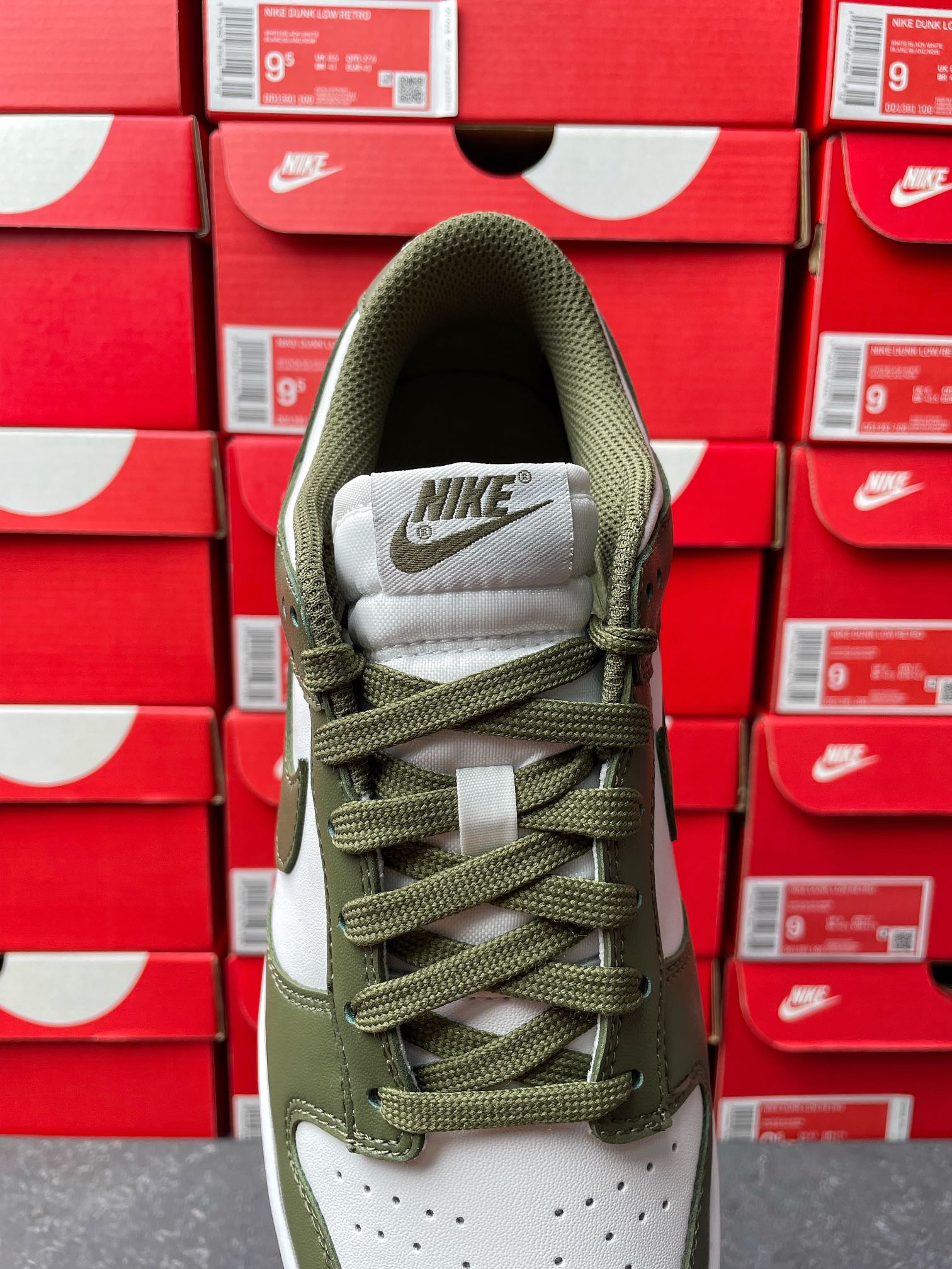 Low-top sneaker collar and tongue in olive green with white “NIKE” patch, lace-up.