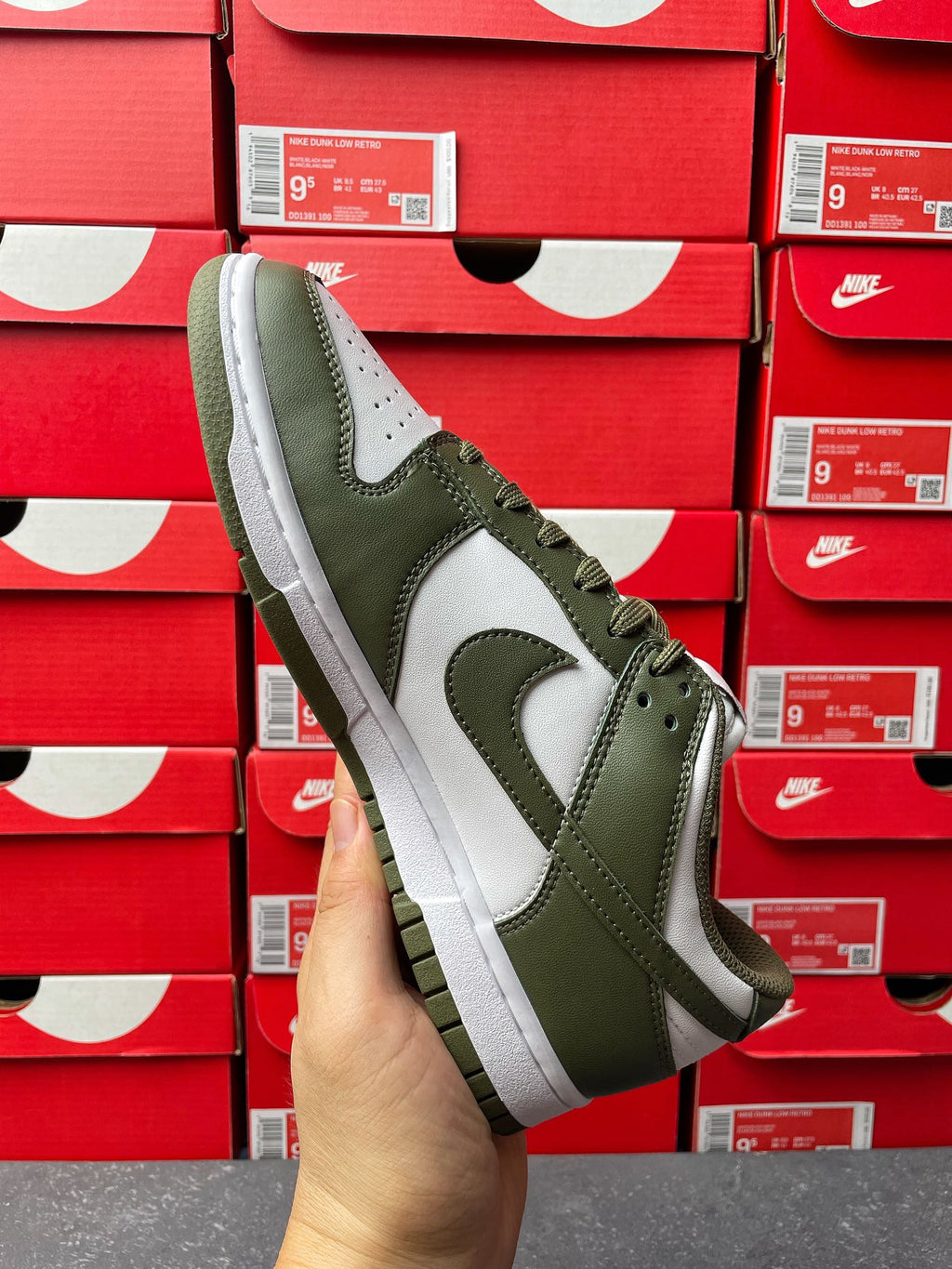 Low-top sneaker front/side angle with olive green overlays, white swoosh, and lace-up.