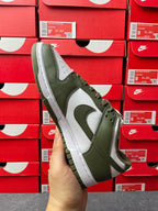 Low-top sneaker front/side angle with olive green overlays, white swoosh, and lace-up.