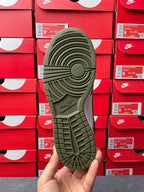 Rubber outsole for low-top sneaker in dark olive green with “NIKE” branding.