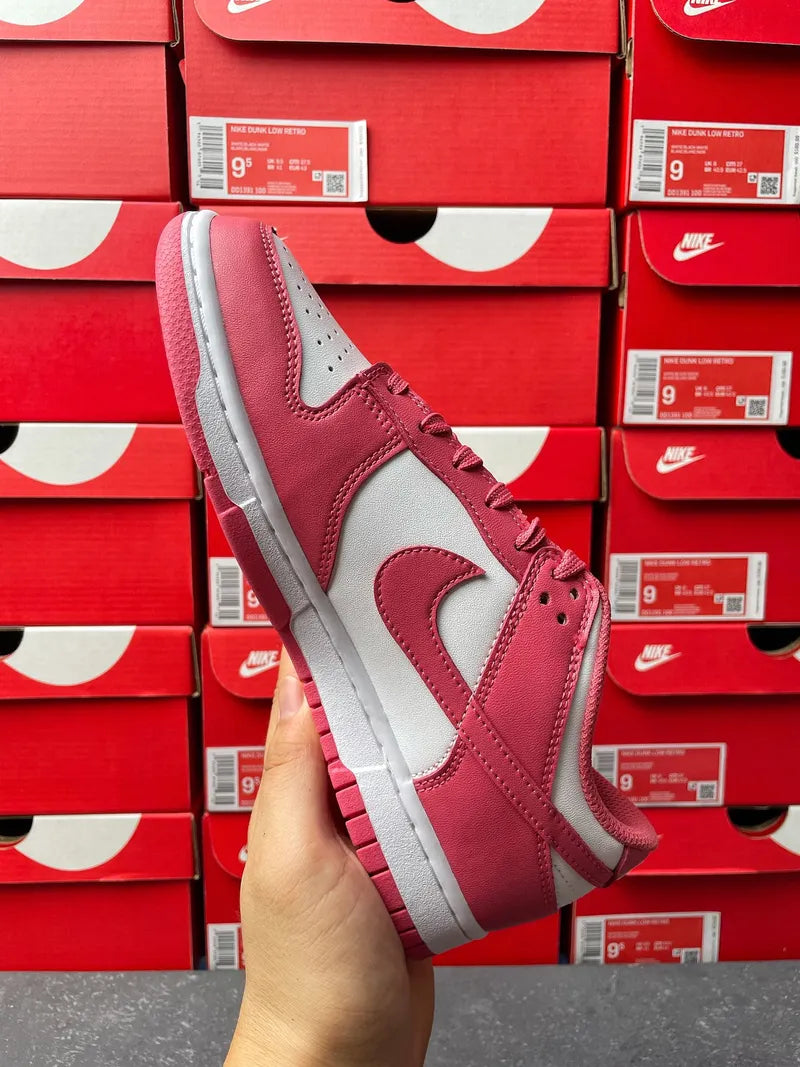 Nike Dunk Low sneakers, angled side view with pink suede overlays and white midsole.