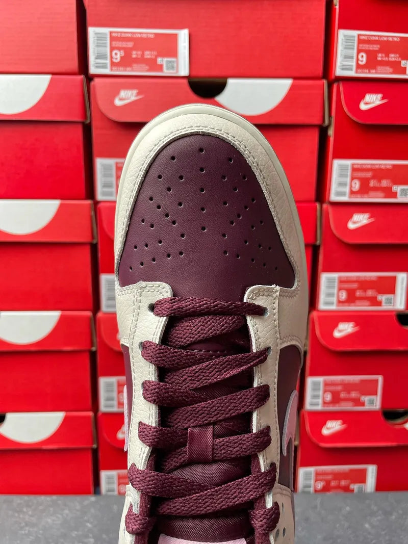 Cream leather low-top sneaker with maroon laces, perforated toe, and maroon eyelets