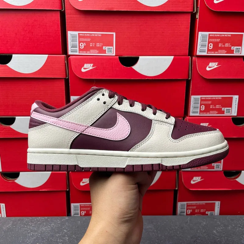 Cream low-top sneaker with soft pink swoosh and maroon toe and side panel accents