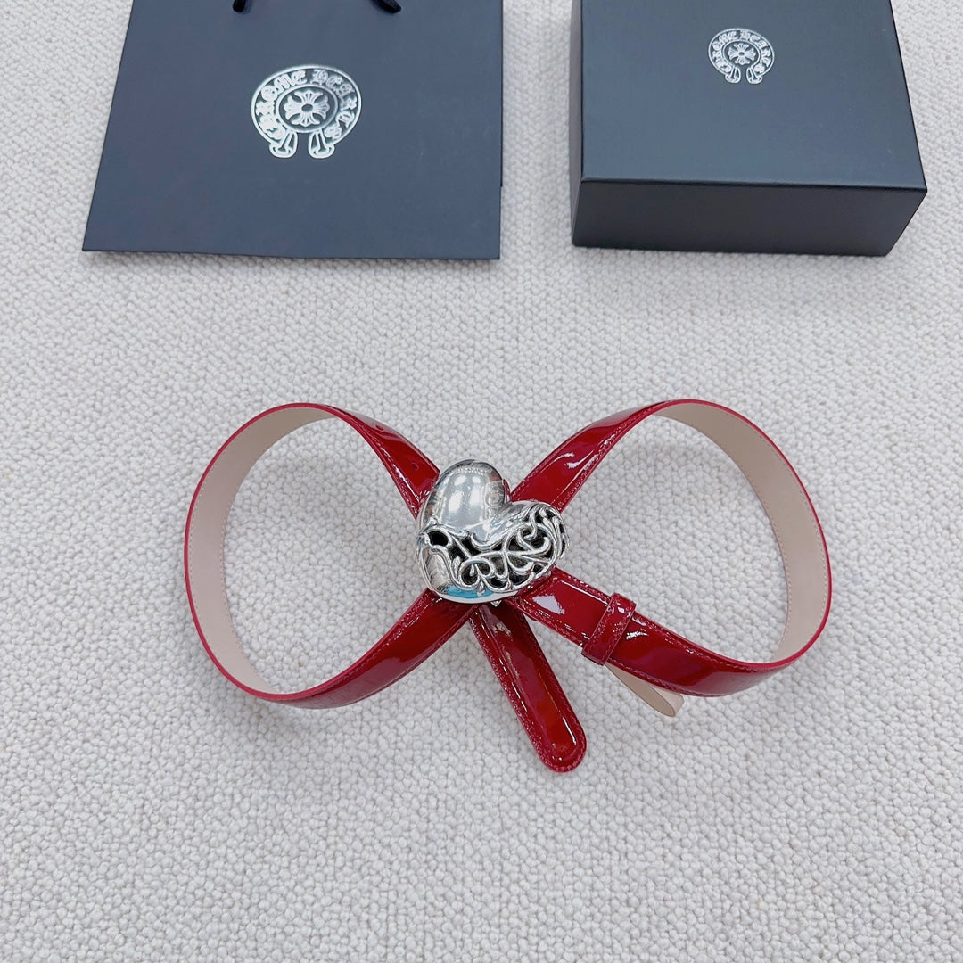 Red patent leather bow belt with silver heart buckle and decorative clasp.
