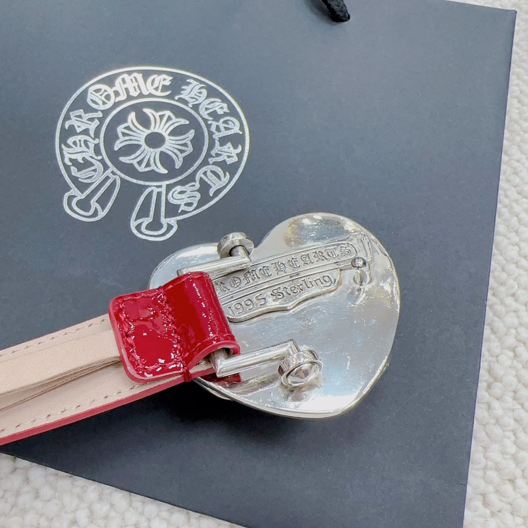 Silver heart buckle with engraved text on a red patent leather belt.