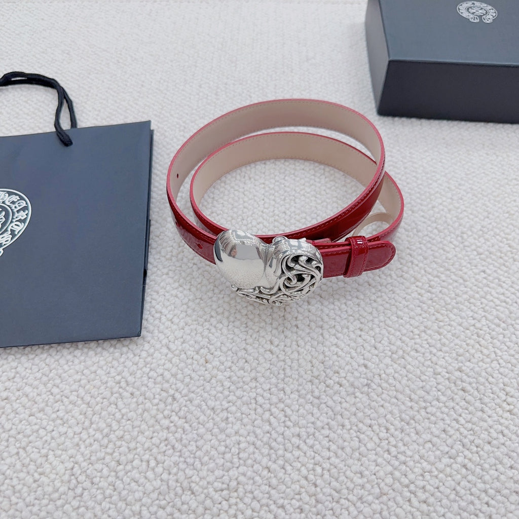 Red patent leather belt cuff with silver heart buckle, resting on fabric.