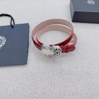 Red patent leather belt cuff with silver heart buckle, resting on fabric.