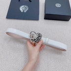 White leather belt with silver heart center buckle, held in hand