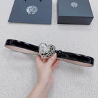 Chrome belt held flat, featuring glossy black strap and silver heart buckle detail.
