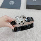 Chrome belt with glossy black leather-look finish and silver heart buckle in close view.