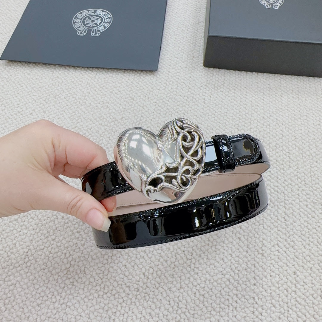 Chrome belt with glossy black leather-look finish and silver heart buckle in close view.