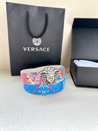 Patterned belt with blue and pink print and large silver lion-head medallion buckle