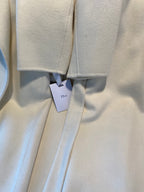 Cream long coat with hanging Dior tags at center seam