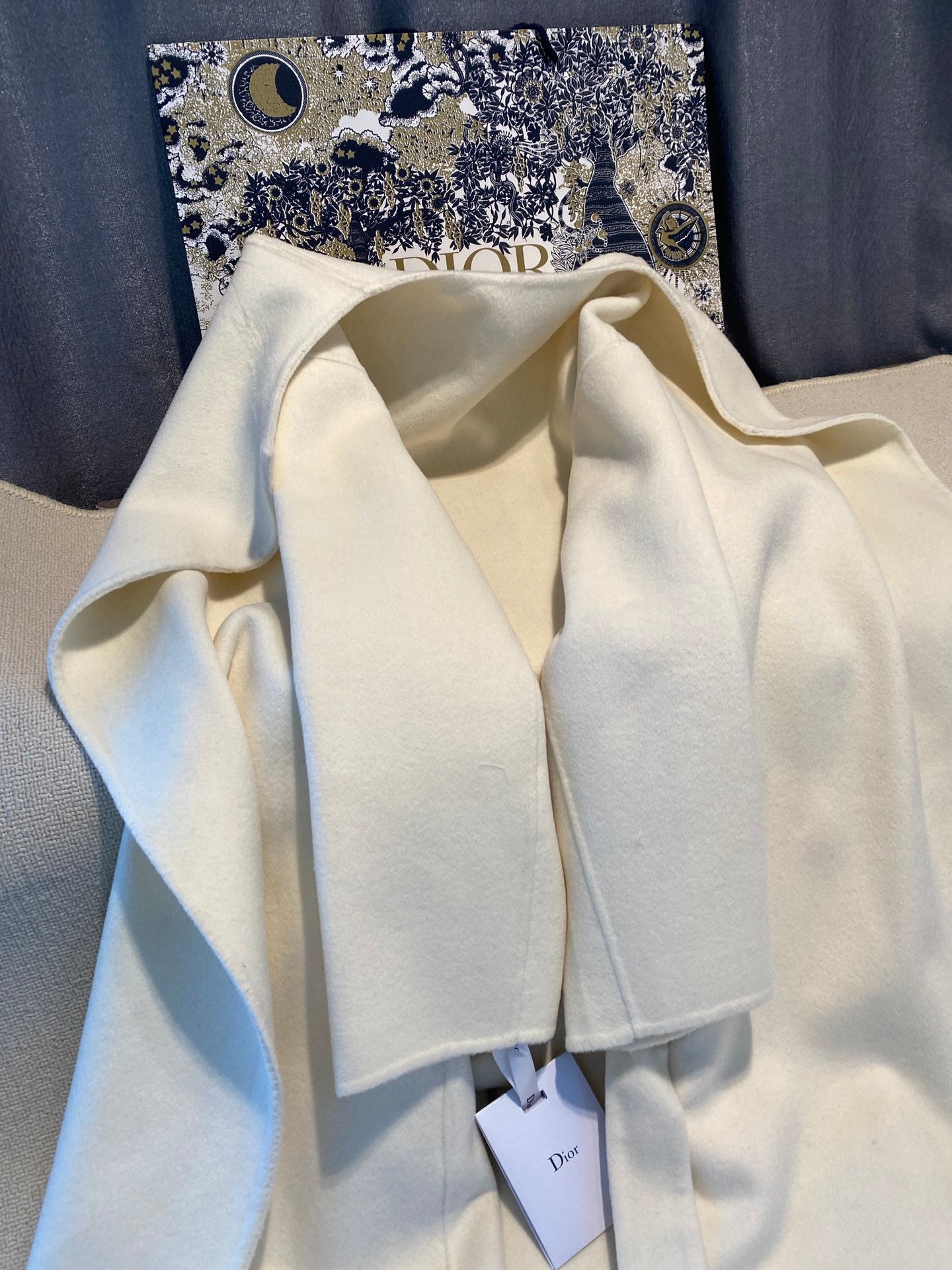 Cream long coat on hanger with open neckline and Dior tags