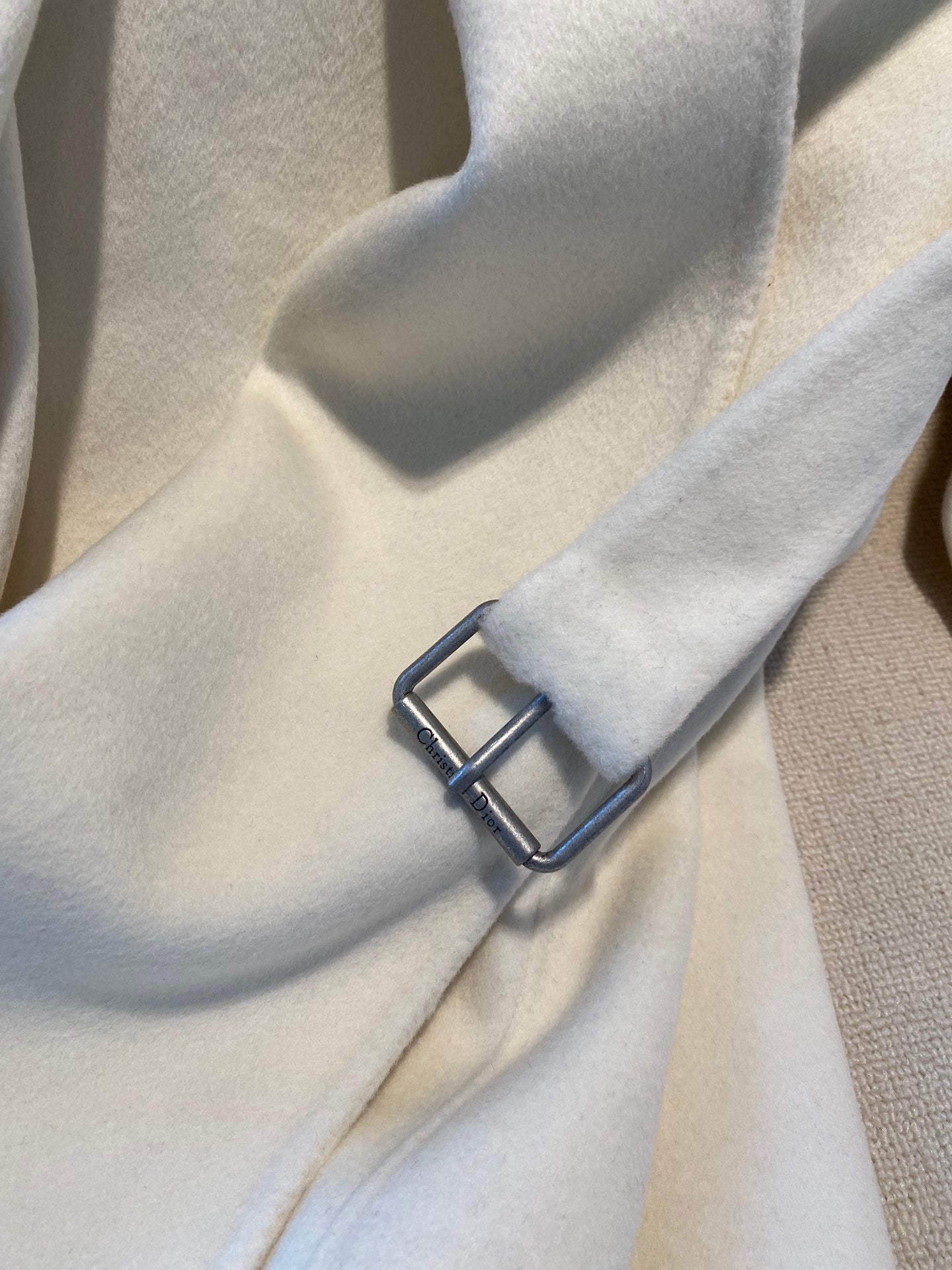 Cream long coat cuff with dark decorative buckle detail