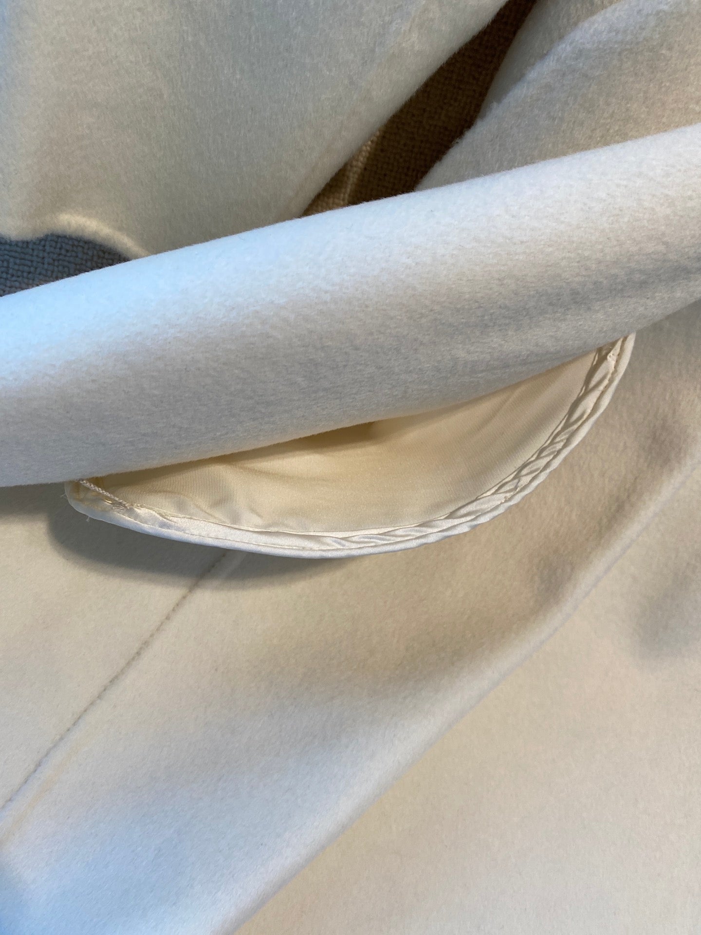 Cream long coat hem and draped inner lining