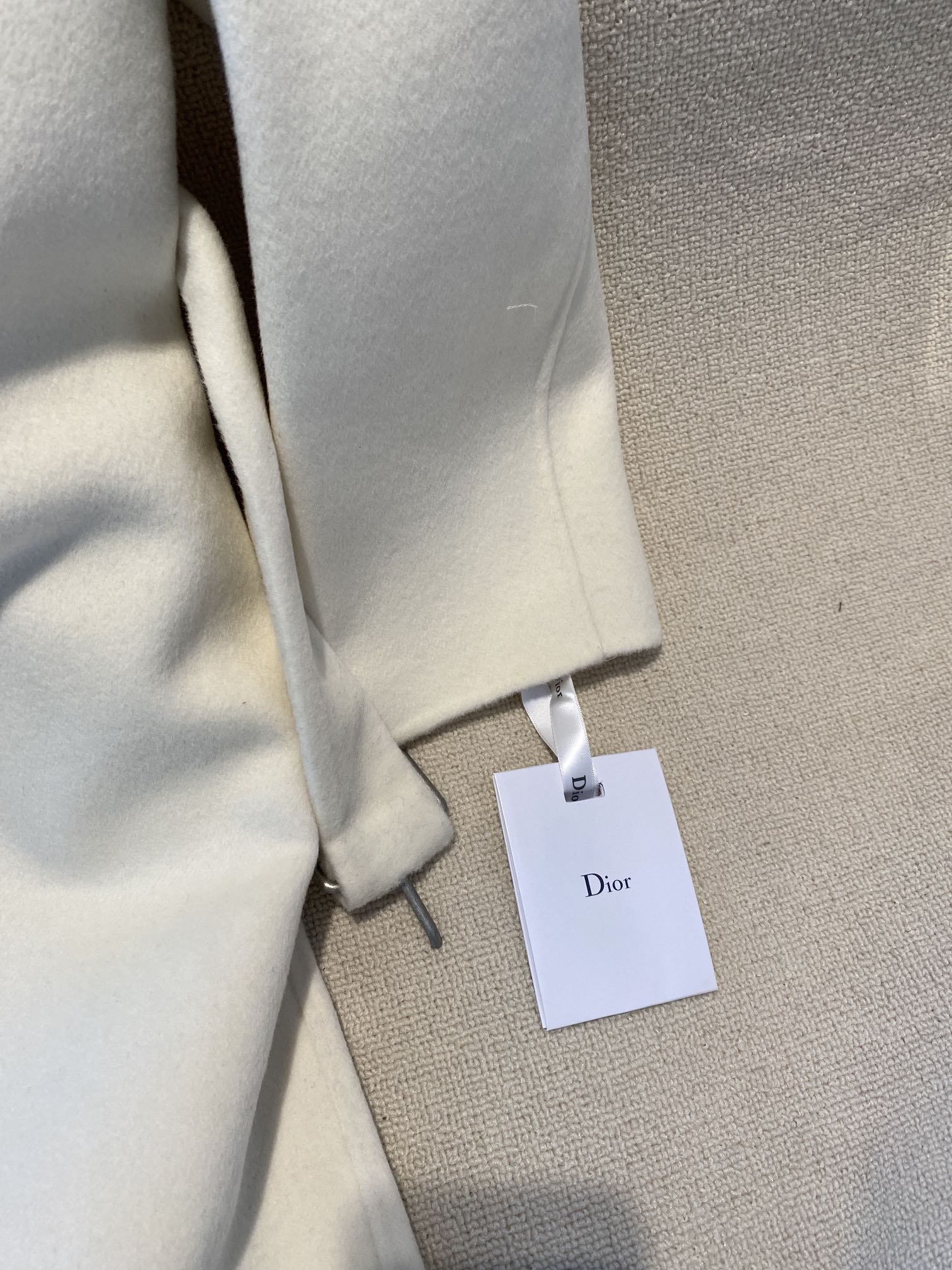 Cream long coat sleeve cuff with white Dior tag