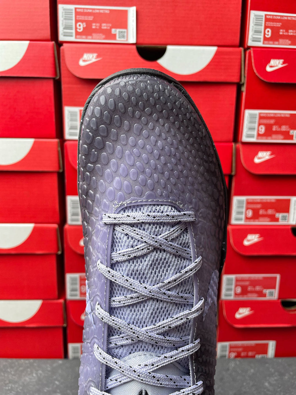 Basketball sneaker with light gray laces and textured dark upper, front view.
