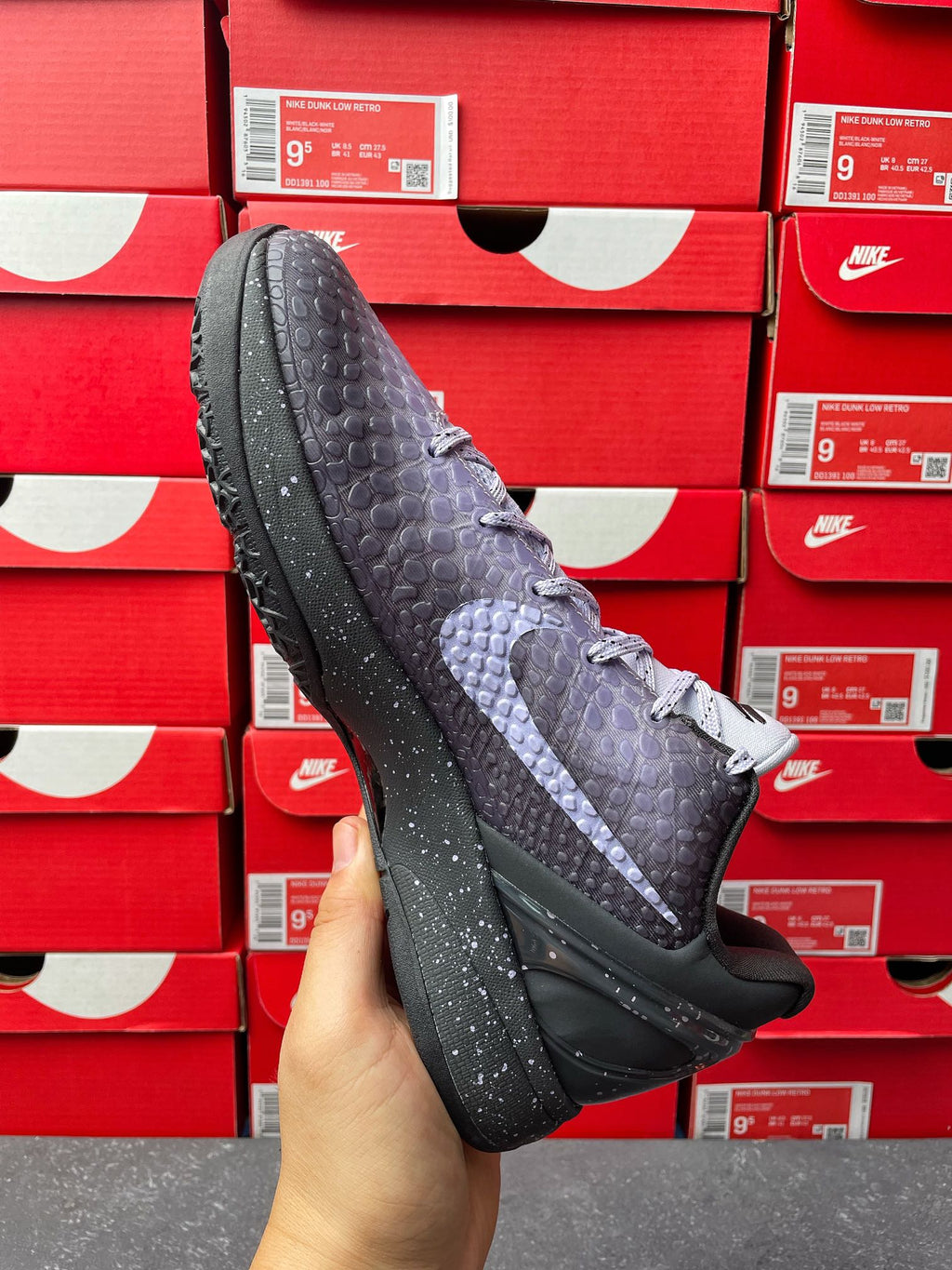 Basketball sneaker with dark gray textured upper and purple accent stripe, side angle.