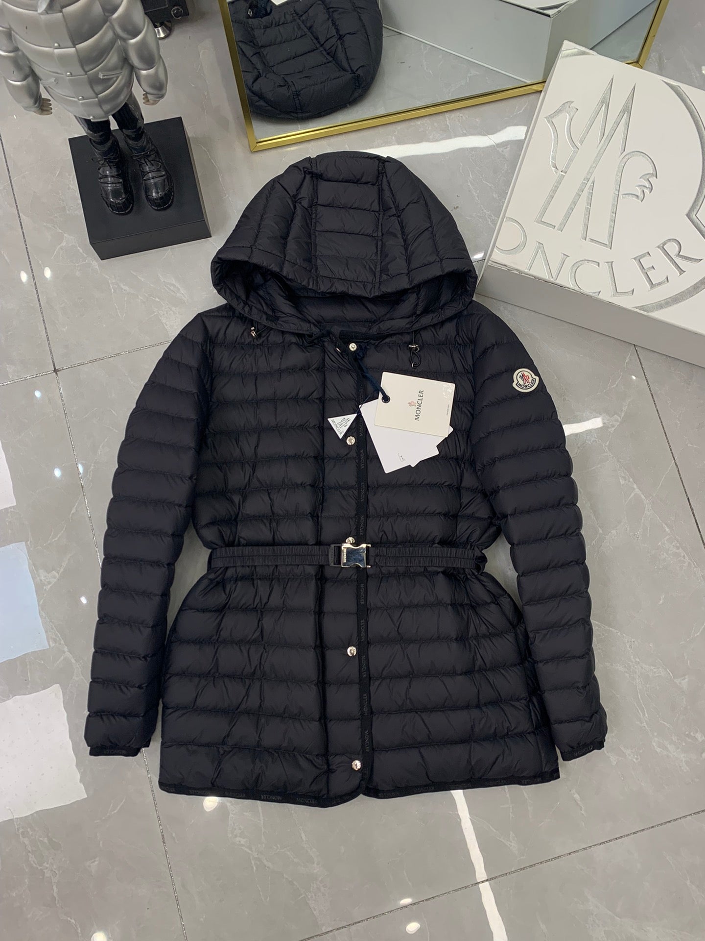 Moncler hooded puffer jacket, dark with front zipper, belt strap, and logo badge