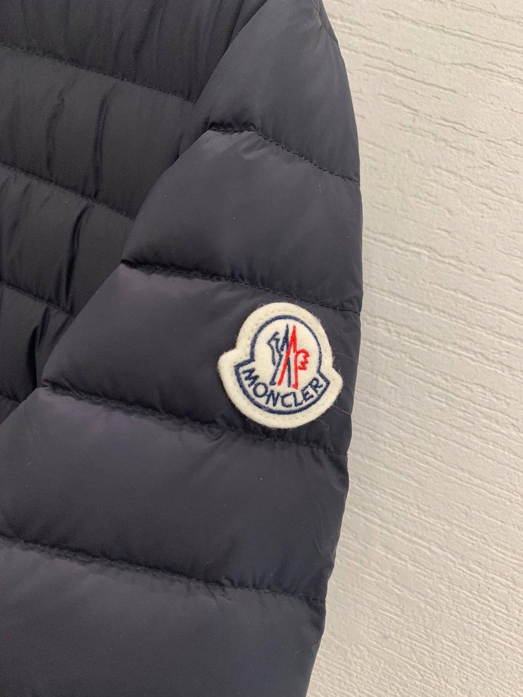 Moncler sleeve logo patch on dark quilted puffer jacket cuff