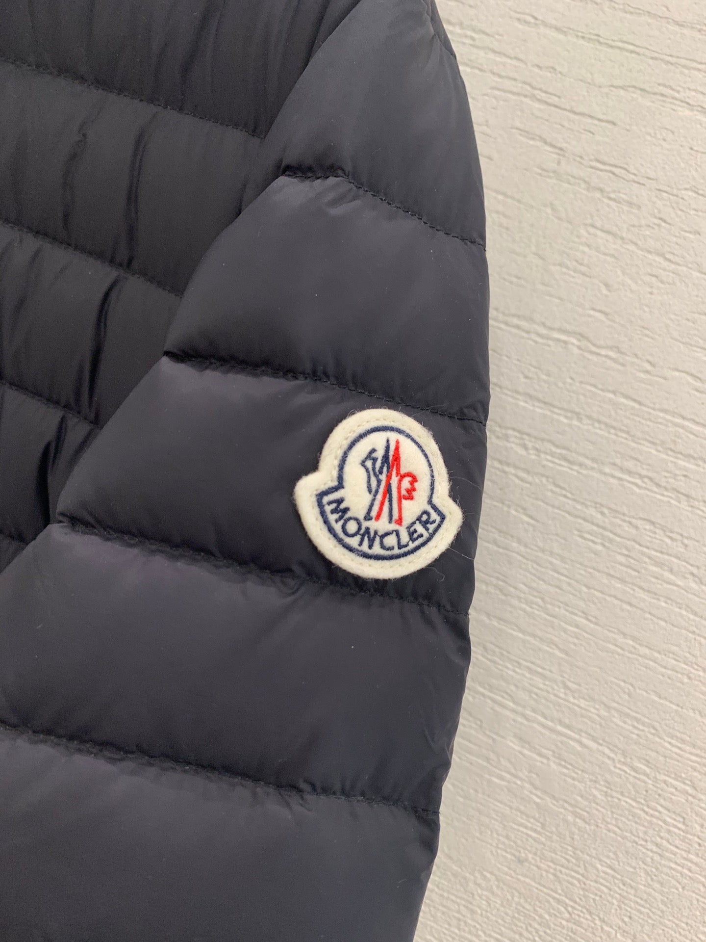 Moncler sleeve logo patch on dark quilted puffer jacket cuff