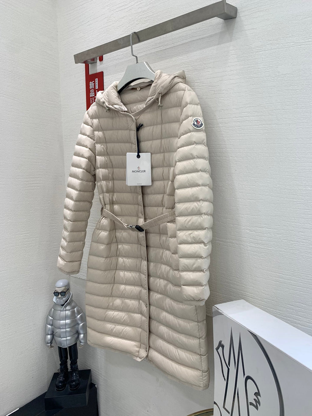 Long beige quilted puffer coat on hanger with hood and front zipper closure