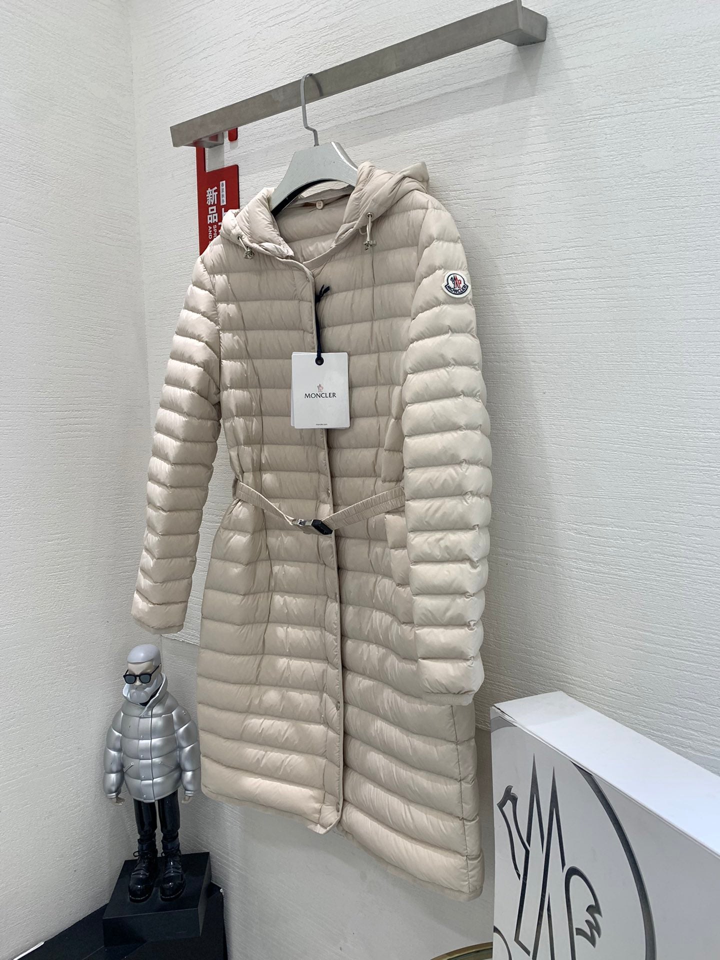 Long beige quilted puffer coat on hanger with hood and front zipper closure