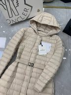 Long beige quilted puffer coat with hood, front button closure, and belt buckle